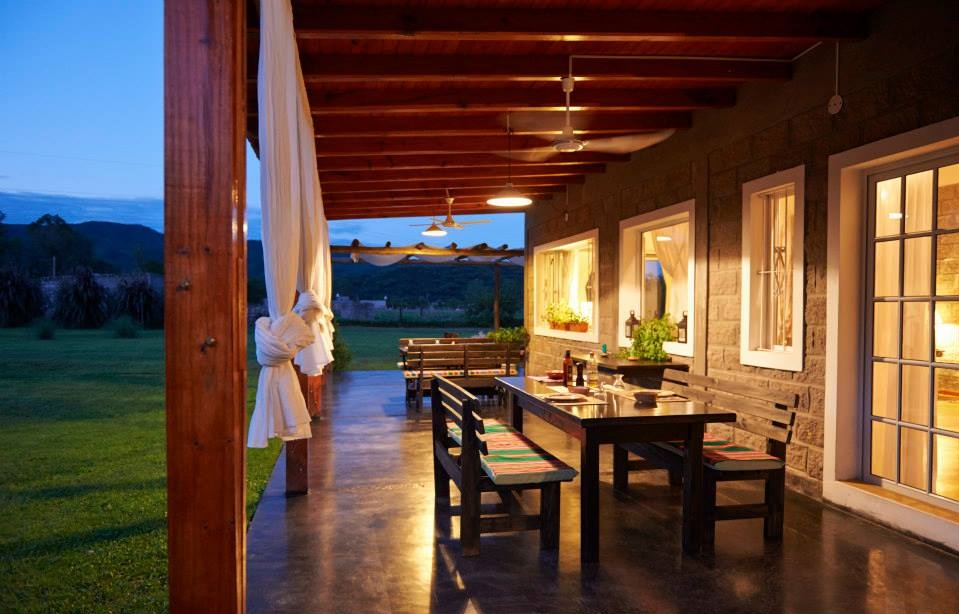 Galería exterior con mesas de madera al atardecer - Finca La Vertiente Salta